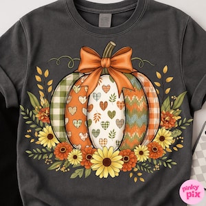 May include: Dark gray t-shirt featuring a colorful pumpkin design. The pumpkin is decorated with plaid, hearts, and knit patterns, topped with an orange bow. Floral accents include sunflowers and fall foliage, creating a seasonal theme.