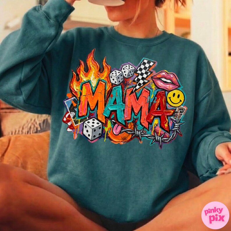 May include: Teal sweatshirt with a colorful graphic that says "MAMA" in graffiti style. The design includes flames, dice, a lightning bolt, lips, a smiley face, and barbed wire.