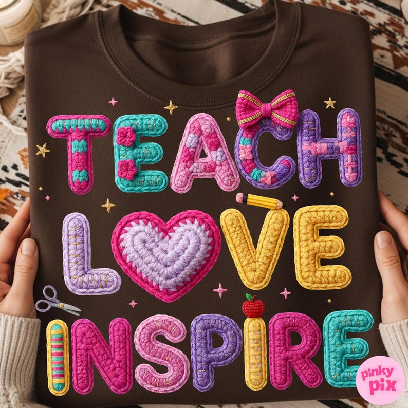 Pu&ograve; includere: Felpa marrone con le parole "TEACH LOVE INSPIRE" in lettere colorate all'uncinetto. Un cuore, un fiocco e una matita all'uncinetto sono presenti nel design. La felpa &egrave; tenuta da una persona.