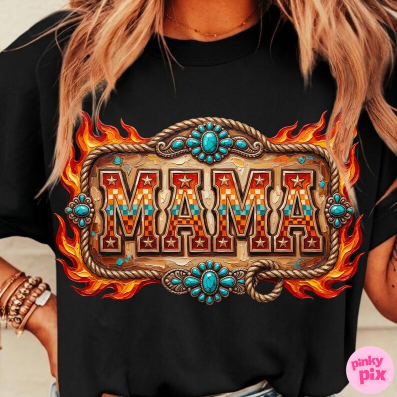 May include: Black t-shirt featuring a decorative design with the word "MAMA" in a western-style font. The design includes a wooden-look frame, turquoise accents, and a flame-like border. The shirt is a casual wear item.