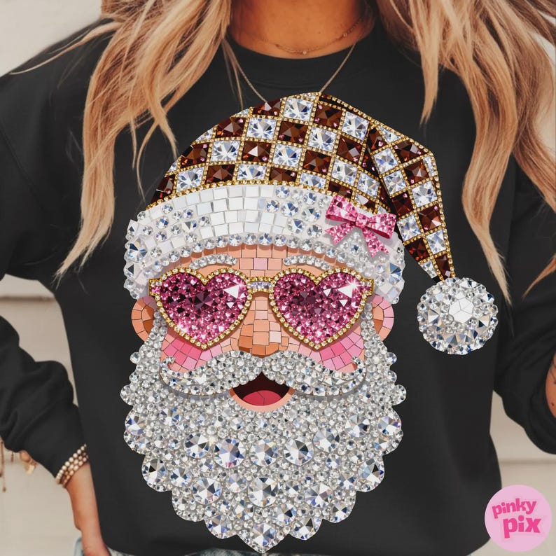 May include: A black sweatshirt featuring a graphic of Santa Claus wearing heart-shaped pink glasses and a Santa hat. The design is composed of a mosaic of sparkling, diamond-like gems in shades of brown, white, pink, and clear, with a small pink bow.
