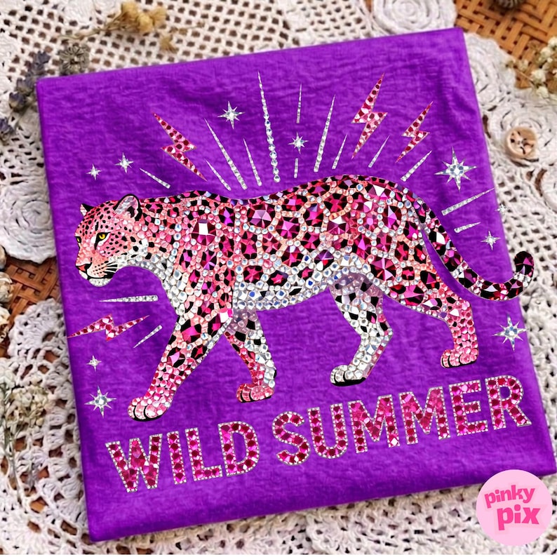 May include: A purple t-shirt featuring a bedazzled pink leopard design with white and pink accents. The words "WILD SUMMER" are spelled out in pink rhinestones. Lightning bolts and stars surround the leopard.