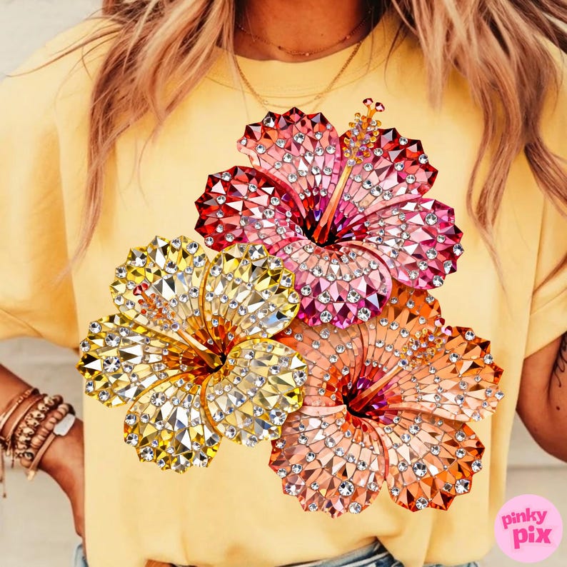 May include: Yellow t-shirt featuring a vibrant design of three hibiscus flowers. The flowers are embellished with sparkling crystals in shades of red, pink, yellow, and orange. The shirt is a solid yellow color.