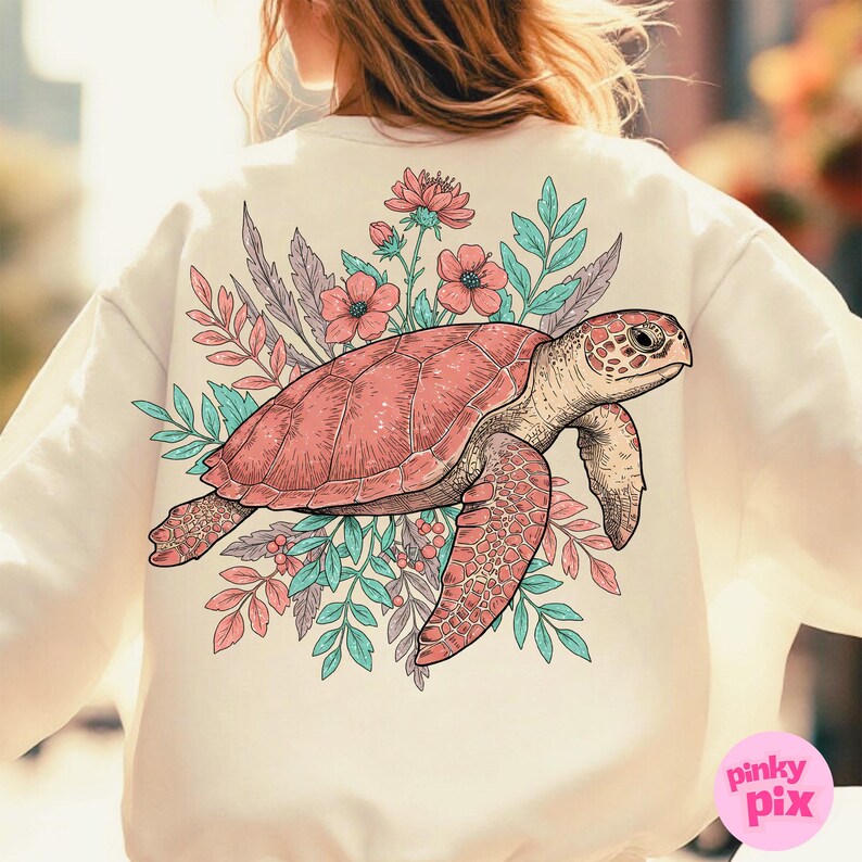 May include: A cream-colored sweatshirt with a pink and green floral design featuring a sea turtle. The turtle is outlined in black and has a detailed shell.