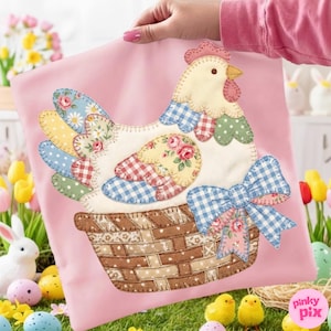 May include: Pink decorative pillow featuring a patchwork chicken design. The chicken has a cream-colored body, colorful patchwork wings, and a red comb. A brown basket and blue gingham bow complete the design, perfect for Easter decor.