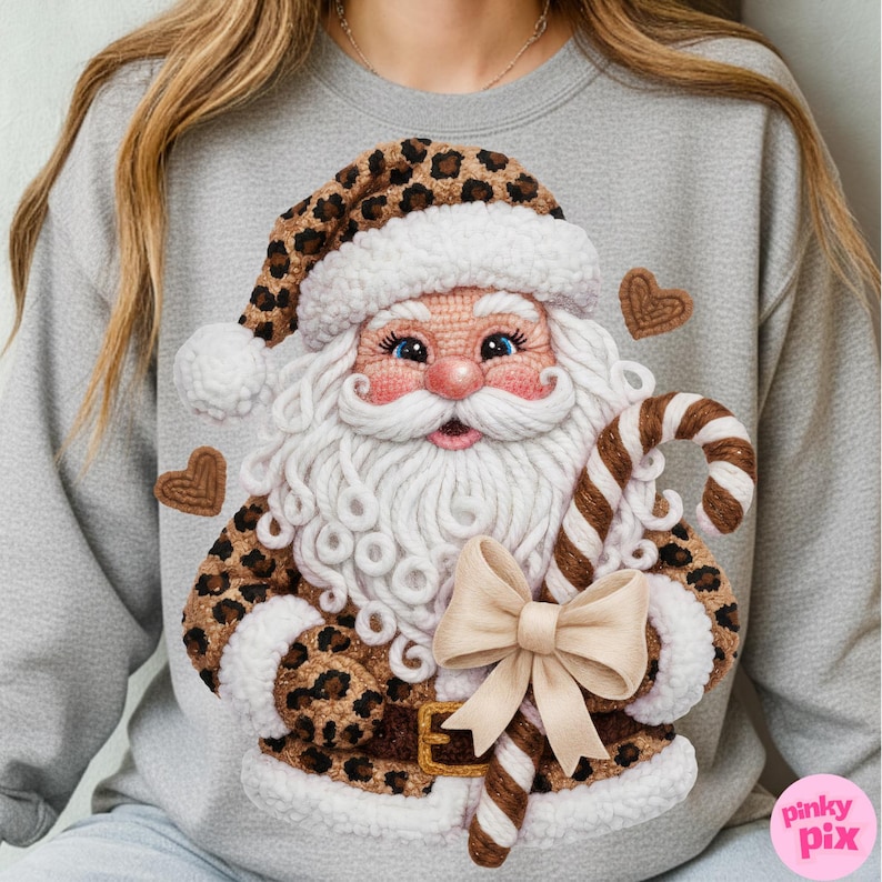 May include: A gray sweatshirt featuring a whimsical Santa Claus design. Santa is depicted with a white beard, blue eyes, and a leopard print hat and coat. He holds a candy cane and a bow. Two heart-shaped cookies are also included in the design.