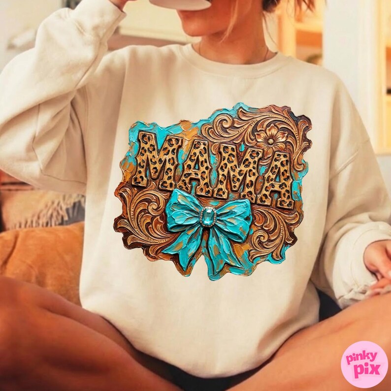 May include: Cream-colored sweatshirt featuring a decorative design with the word "MAMA" in a leopard print font. The design includes a turquoise bow and floral accents, set against a brown, textured background.