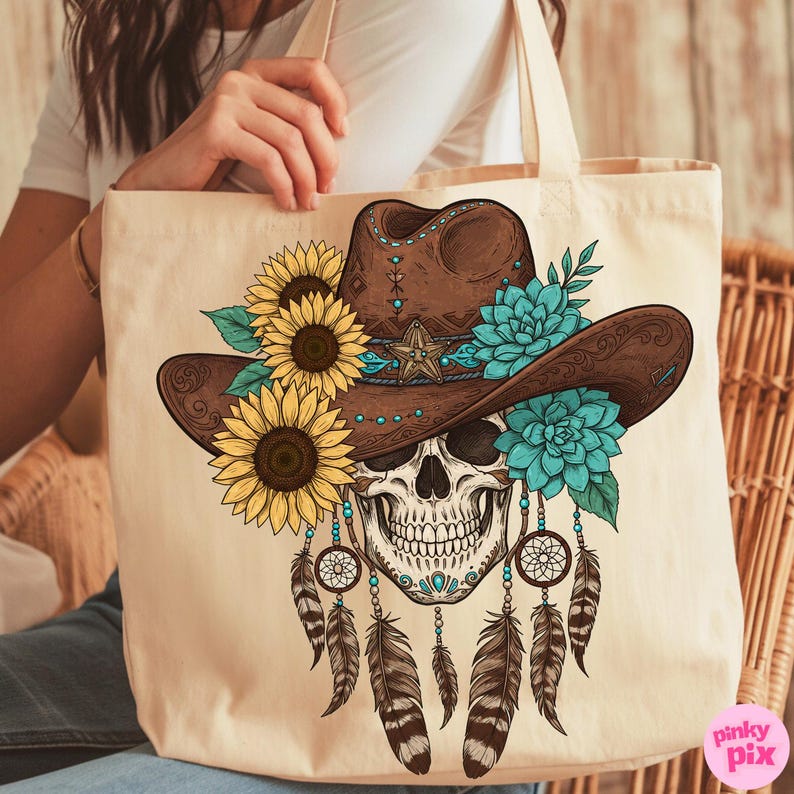 Op de afbeelding: Beige draagtas met een gedetailleerde illustratie van een schedel met een bruine cowboyhoed versierd met zonnebloemen, turquoise bloemen en een ster. Dromenvangers en veren hangen eronder.