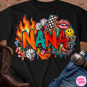 May include: Black t-shirt with a colorful graphic design. The design features the word "NANA" in orange, red, and teal letters, surrounded by flames, dice, a lightning bolt, lips, a smiley face, and barbed wire.
