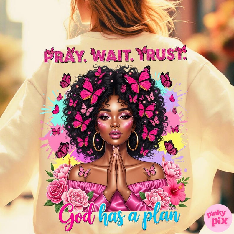 May include: Cream-colored sweatshirt featuring a vibrant illustration of a woman with butterflies in her hair and around her. The design includes the text "PRAY. WAIT. TRUST." at the top and "God has a plan" at the bottom, with pink and blue accents.