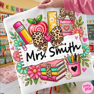 Könnte beinhalten: Ein weißes Kissenbezug mit einem farbenfrohen Lehrer-Themen-Design. Das Design umfasst einen Bleistift, einen Apfel, ein Lineal, eine Kaffeetasse, Bücher und Bleistifte. Der Name "Mrs. Smith" steht auf linierten Papier. Blumen- und Herzmotive ergänzen das Design.