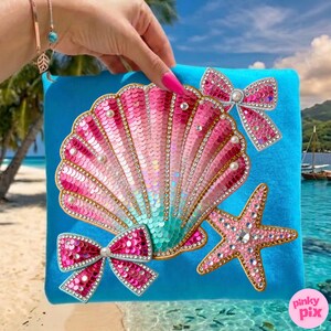 May include: A turquoise blue clutch featuring a large, sequined seashell design in shades of pink and teal. Embellished with faux pearls, rhinestones, and two sequined bows. A pink starfish and the text "pinky pix" complete the design.