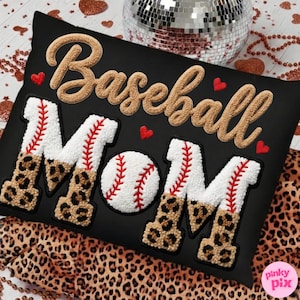 May include: Black cushion featuring the text "Baseball Mom" in a textured, tan font. The word "MOM" is in white with red stitching and leopard print accents. A baseball is in the center. Red heart accents are scattered around the text.