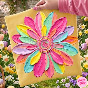 May include: A vibrant, textured painting of a large flower with colorful petals in shades of pink, yellow, blue, and orange. The artwork is on a square, yellow canvas, held by a person. The flower's center has a spiral design.