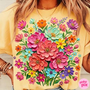 May include: A yellow t-shirt featuring a vibrant, 3D-effect floral design. The bouquet includes pink, orange, blue, and purple flowers with green stems and leaves. The shirt has a crew neck and short sleeves.