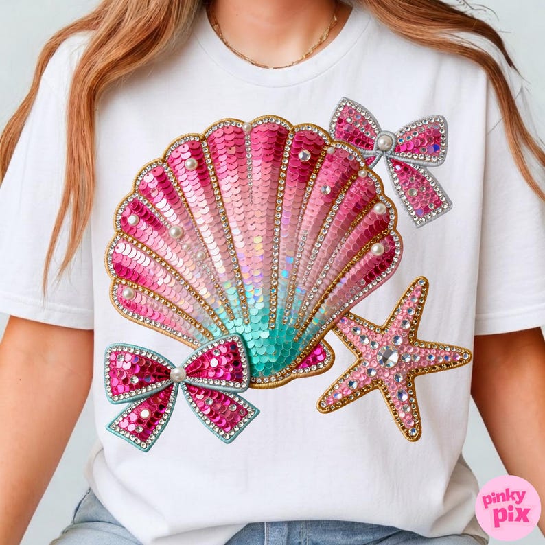 May include: White t-shirt featuring a seashell design with pink sequins, pearls, and a turquoise gradient. The design includes two pink sequined bows and a pink starfish, all embellished with rhinestones. The shirt has a crew neck.