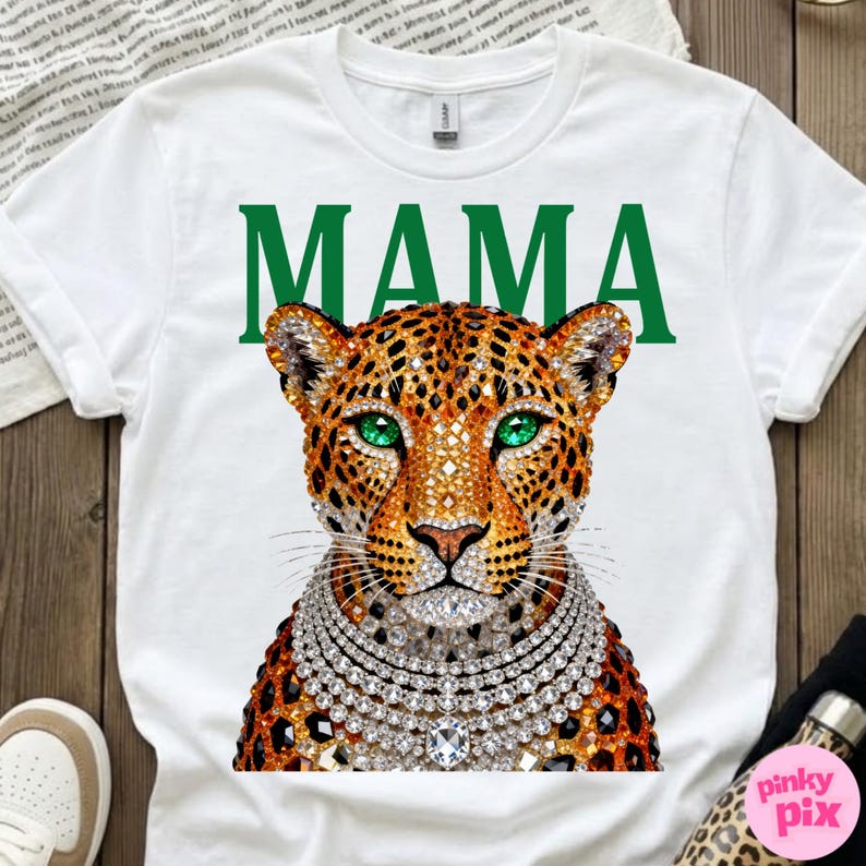 May include: White t-shirt with a leopard design, green eyes, and a diamond necklace. The word "MAMA" is printed in green above the leopard's head. The leopard has a brown and orange spotted coat.