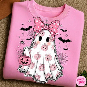May include: Pink sweatshirt with a ghost design. The ghost has a pink bow and a pumpkin-shaped candy bucket. The ghost is decorated with pink pumpkins and surrounded by bats, spiders, and spiderwebs. The sweatshirt has a crew neck.