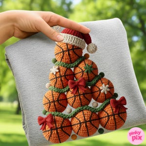 May include: A gray sweatshirt with a crocheted basketball Christmas tree design. The tree is made of orange basketballs with black lines, green garland, red bows, and white snowflake accents. A small Santa hat tops the tree.