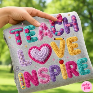 Pu&ograve; includere: Una felpa grigia con le parole "TEACH LOVE INSPIRE" in lettere colorate all'uncinetto. Il design include un cuore, una matita, una mela e un fiocco. La felpa &egrave; tenuta da una mano.