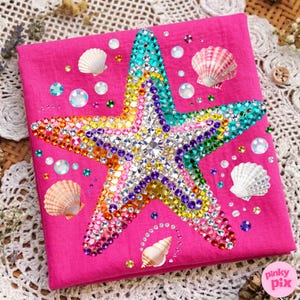 May include: A hot pink square with a large, bejeweled starfish in the center. The starfish is covered in colorful rhinestones. Scattered around the starfish are seashells and iridescent beads. The image has a beach or ocean theme.