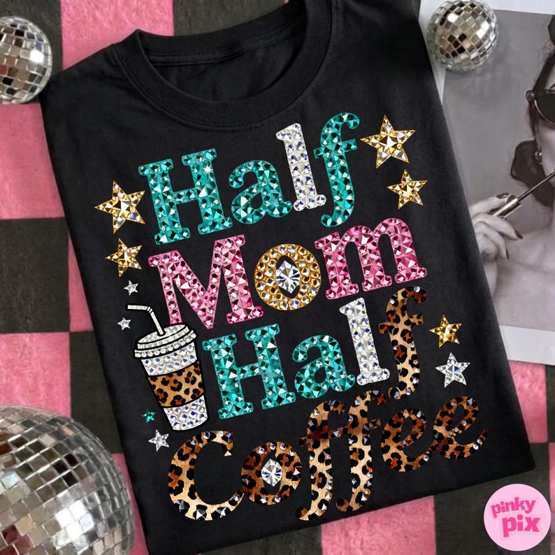Może przedstawiać: Czarny t-shirt z napisem "Half Mom Half Coffee" w kolorowym, wysadzanym klejnotami wzorze. Projekt zawiera grafikę filiżanki kawy i akcenty gwiazd. Jest to odzież codzienna.