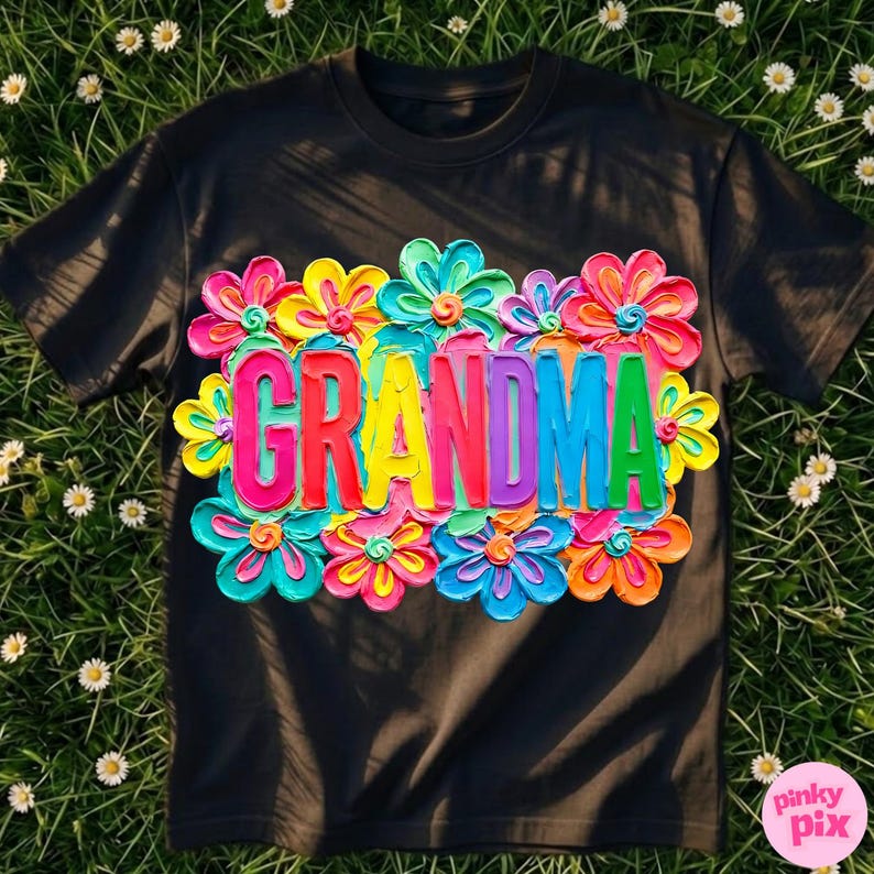 May include: Black t-shirt with the word "GRANDMA" in colorful, raised letters, surrounded by vibrant, textured flowers in shades of pink, yellow, blue, and green. The design is centered on the shirt.