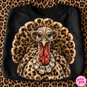 May include: A black sweatshirt featuring a graphic of a turkey with a leopard print pattern on its feathers. The turkey wears leopard print cat-eye glasses and a large, clear crystal statement necklace. The design is centered on the front.