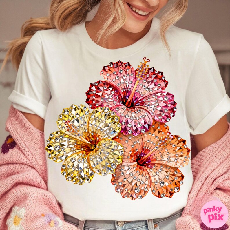 May include: White t-shirt featuring a vibrant floral design. The graphic showcases three hibiscus flowers in shades of red, orange, and yellow, each adorned with a sparkling, gem-like texture. The shirt has short sleeves and a crew neck.