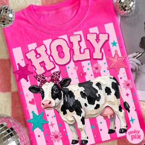 May include: A bright pink t-shirt with the word "HOLY" in bubble letters and a cartoon cow wearing a leopard print bow. The shirt has a vertical striped design with stars and flowers.