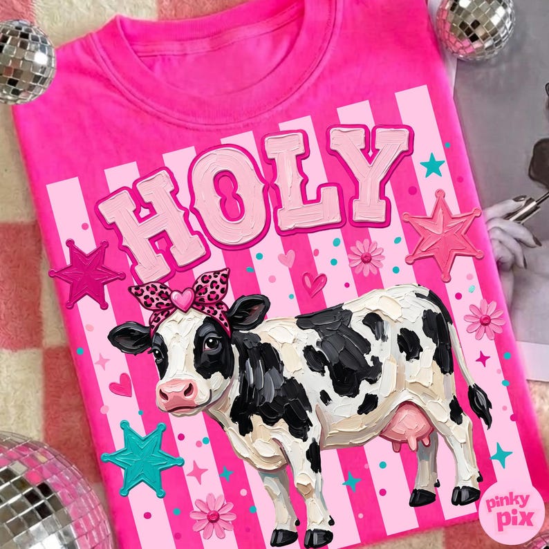 May include: A bright pink t-shirt with the word "HOLY" in bubble letters and a cartoon cow wearing a leopard print bow. The shirt has a vertical striped design with stars and flowers.