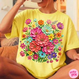 May include: Yellow t-shirt featuring a vibrant floral bouquet design. The bouquet includes pink, red, orange, blue, and purple flowers. The shirt has a round neckline and short sleeves. The text "pinky pix" is in the lower right corner.