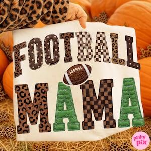 May include: A cream-colored sweatshirt featuring the text FOOTBALL MAMA in large, stitched-style letters. The letters display various patterns including brown leopard print, black and white checkered squares, and solid green with visible stitching.