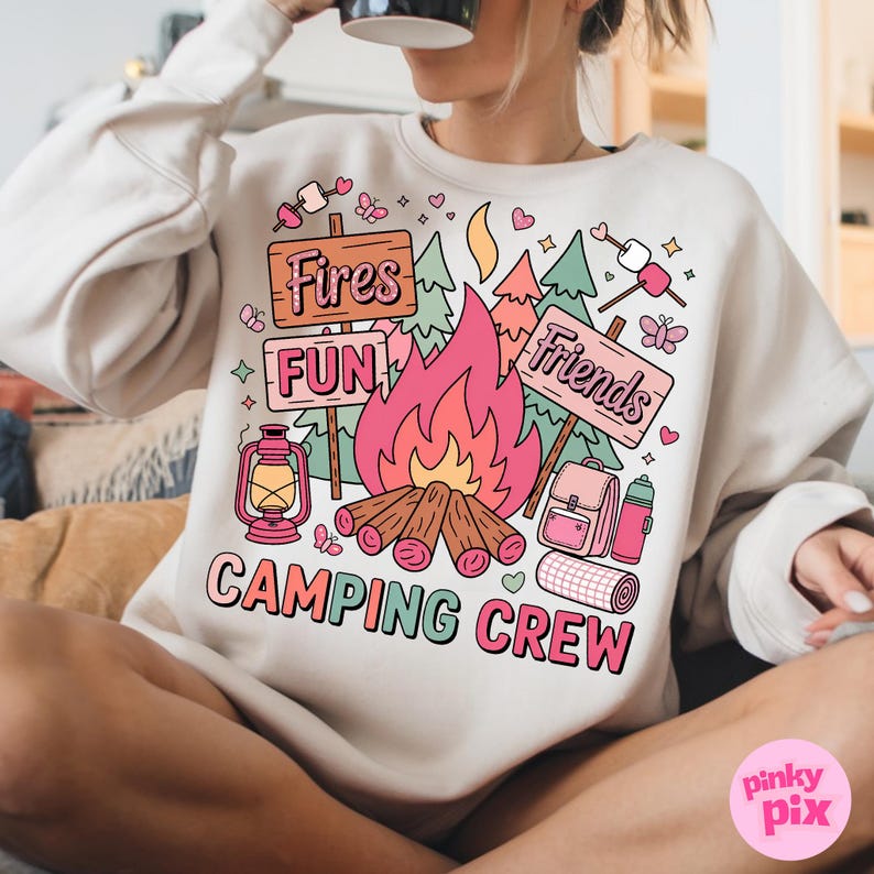 May include: A cream-colored sweatshirt with a camping-themed graphic. The design features a campfire, signs that read "Fires", "Fun", and "Friends", and camping accessories. The words "Camping Crew" are printed at the bottom.