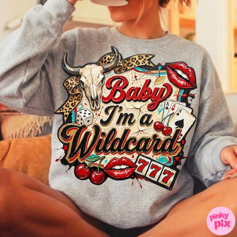 Może przedstawiać: Szara bluza z nadrukiem przedstawiającym czaszkę byka, kości do gry, karty do gry, wiśnie i czerwone usta. Tekst "Baby I'm a Wildcard" jest wyświetlany w stylu vintage.