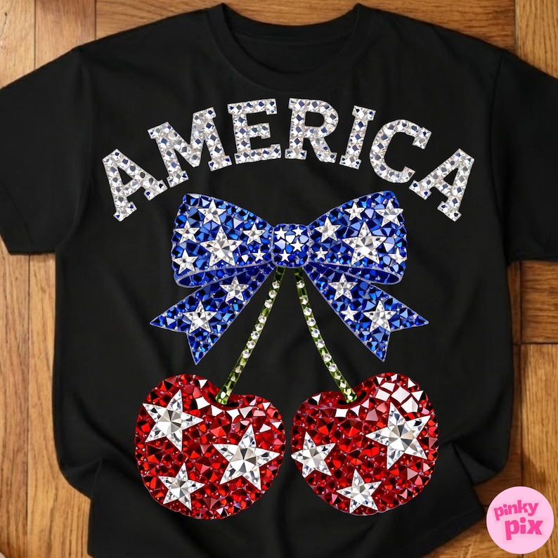 May include: Black t-shirt with the word "AMERICA" in silver rhinestones. A blue bow with white star accents and red cherries with white star accents complete the patriotic design.