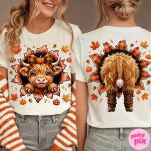 May include: A white t-shirt featuring a graphic of a fluffy Highland cow with a plaid bow on the front and the back view of the same cow wearing leg warmers. The design is framed by a torn paper effect with autumn leaves, acorns, and pumpkins.