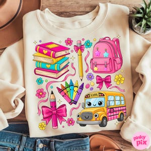 Pu&ograve; includere: Felpa color crema con grafica a tema scolastico colorata. Il design include una pila di libri, uno zaino rosa, un autobus scolastico giallo, matite, pastelli e fiori. L'autobus scolastico ha la scritta "SCHOOL".