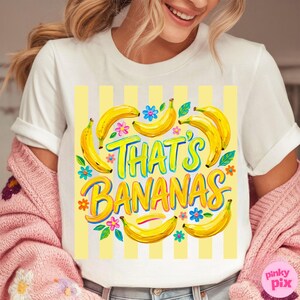 Pu&ograve; includere: T-shirt bianca con una grafica colorata che dice "That's Bananas". Il design presenta banane gialle, fiori e uno sfondo a righe gialle. Il testo &egrave; in colori vivaci e giocosi.