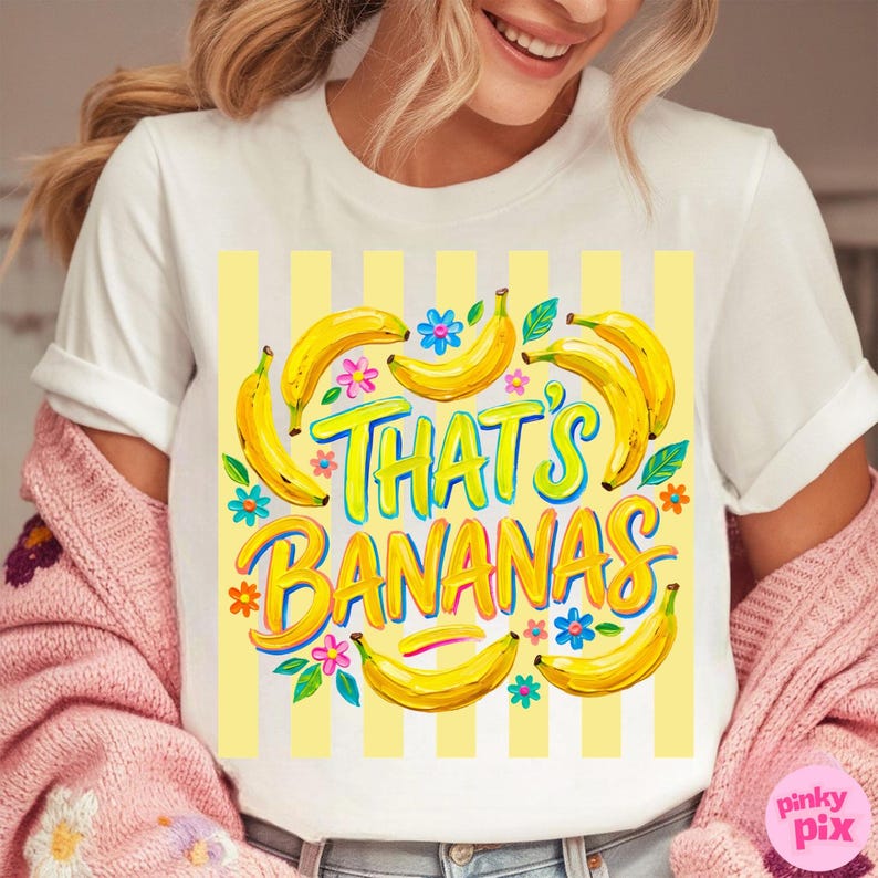 Pu&ograve; includere: T-shirt bianca con una grafica colorata che dice "That's Bananas". Il design presenta banane gialle, fiori e uno sfondo a righe gialle. Il testo &egrave; in colori vivaci e giocosi.