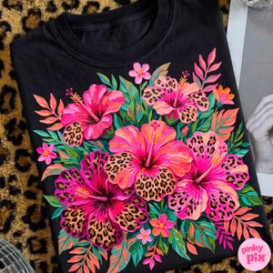 May include: Black crew neck sweatshirt featuring a vibrant floral design. The design includes pink and orange hibiscus flowers with leopard print centers, surrounded by green and orange leaves. The text "pinky pix" is in the lower right corner.