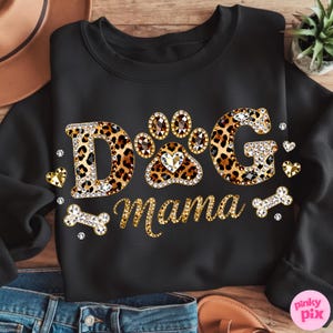 May include: Black sweatshirt with the text "DOG Mama" in a leopard print design, embellished with rhinestones. The design includes paw prints, hearts, and a bone. A stylish and comfortable apparel item for dog lovers.