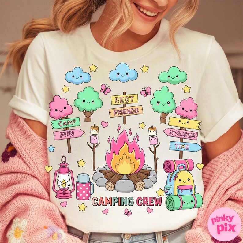 May include: White t-shirt with a colorful camping-themed graphic. The design includes a campfire, trees, clouds, butterflies, and the words "Camping Crew," "Camp Fun," and "S'mores Time."