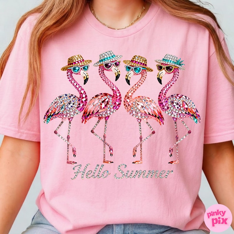 May include: Pink t-shirt featuring four bejeweled flamingo illustrations wearing sunglasses and hats. The flamingos have pink, orange, and crystal-like details. The text "Hello Summer" is below the flamingos.