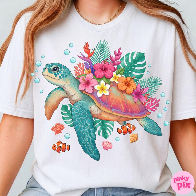 May include: White t-shirt featuring a colorful sea turtle design. The turtle has a blue head and flippers, a shell adorned with flowers, and is surrounded by bubbles, coral, and fish. The design includes pink, orange, and yellow flowers.