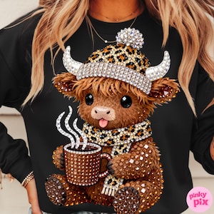 May include: Black sweatshirt featuring a rhinestone-studded cartoon Highland cow wearing a leopard print hat and scarf. The cow is holding a rhinestone-covered mug with steam rising from it. The design includes a rhinestone pom-pom on the hat and rhinestone horns.