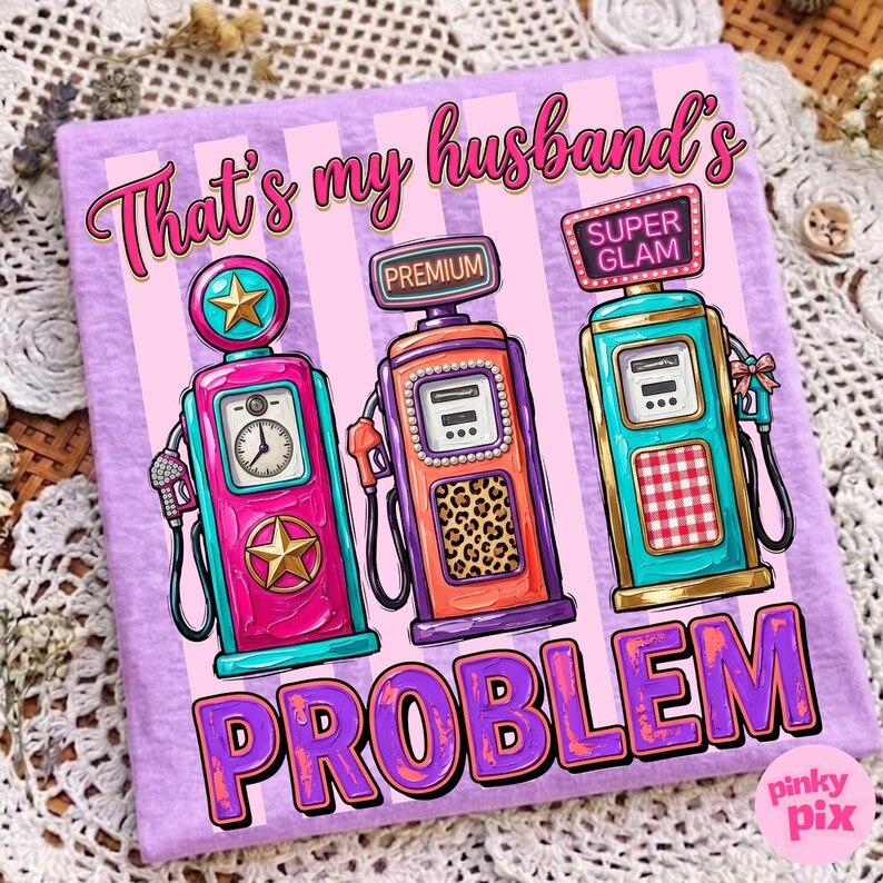 May include: A lilac-colored t-shirt with a graphic of three vintage gas pumps in pink, orange, and teal. The text "That's my husband's PROBLEM" is written across the top and bottom in pink and purple. The gas pumps have star and leopard print details.