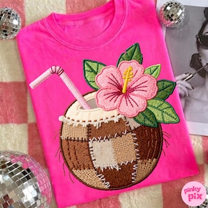 May include: A vibrant pink sweatshirt with an embroidered coconut drink design. The coconut is brown with a patchwork design, topped with a pink hibiscus flower, green leaves, and a pink straw. The text "pinky pix" is in the bottom right corner.