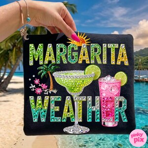 Peut inclure: T-shirt noir avec l'inscription scintillante "MARGARITA WEATHER" en vert et jaune. Le motif comprend un verre &agrave; margarita, un cocktail rose, un palmier et un soleil.