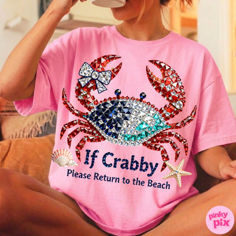 May include: Pink t-shirt featuring a bejeweled crab design with red, blue, and white crystals. The crab has a bow on one claw. Text on the shirt reads "If Crabby, Please Return to the Beach". A seashell and starfish are also on the shirt.